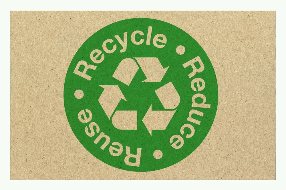 Green recycling symbol with the words Recycle, Reduce, Reuse on brown cardboard Green recycling symbol with the words Recycle, Reduce, Reuse on brown cardboard