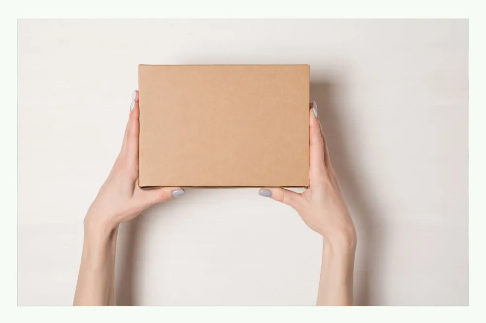 Two hands holding a brown cardboard box Two hands holding a brown cardboard box
