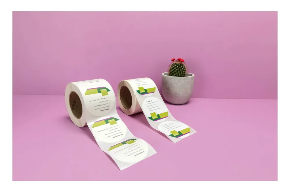 Zwei Rollen mit Runden und bedruckten Etiketten vor einem violetten Hintergrund Zwei Rollen mit Runden und bedruckten Etiketten vor einem violetten Hintergrund