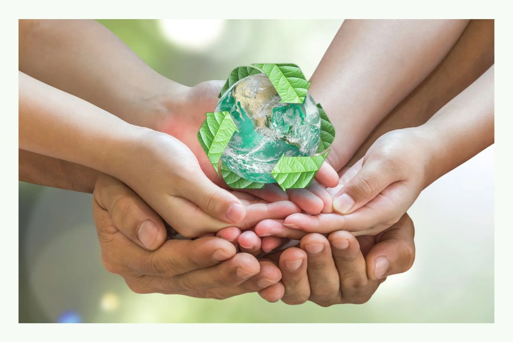 Several hands holding a green recycling symbol made of glass Several hands holding a green recycling symbol made of glass